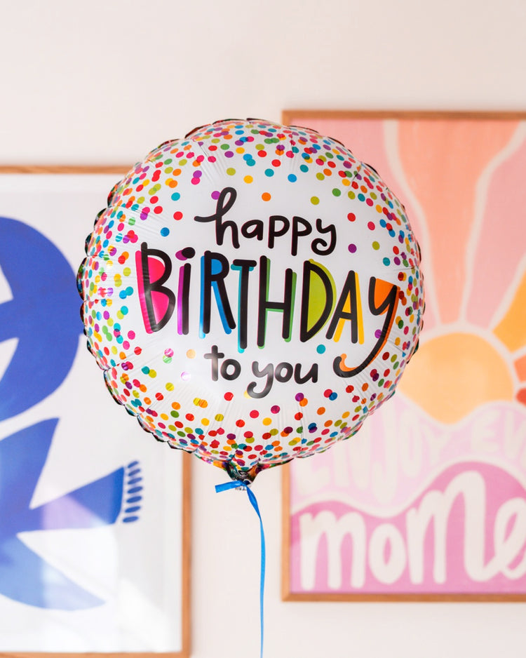 Ballon 'Happy Birthday' avec confettis colorés en gros plan.