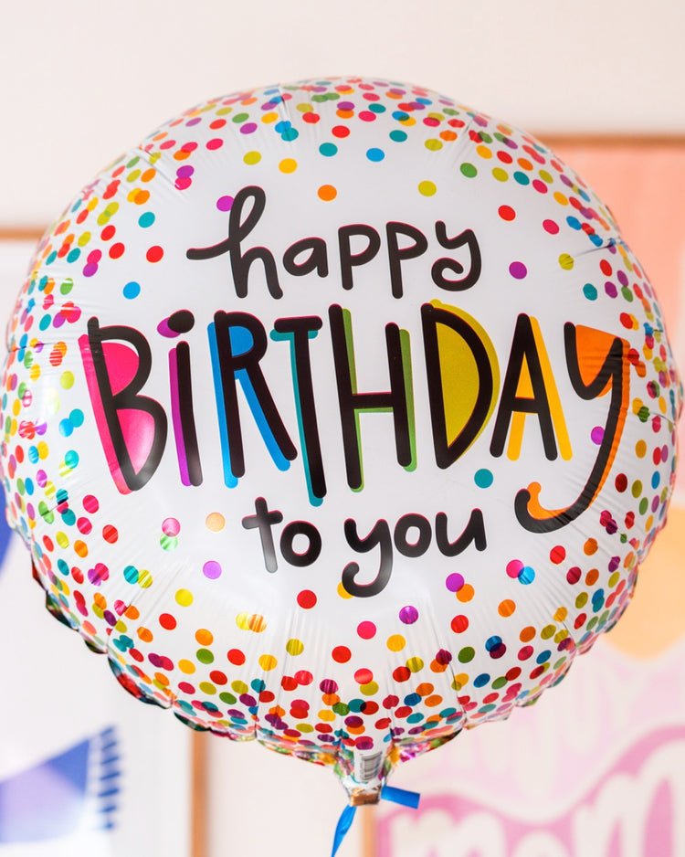 Ballon 'Happy Birthday' avec confettis colorés en gros plan.