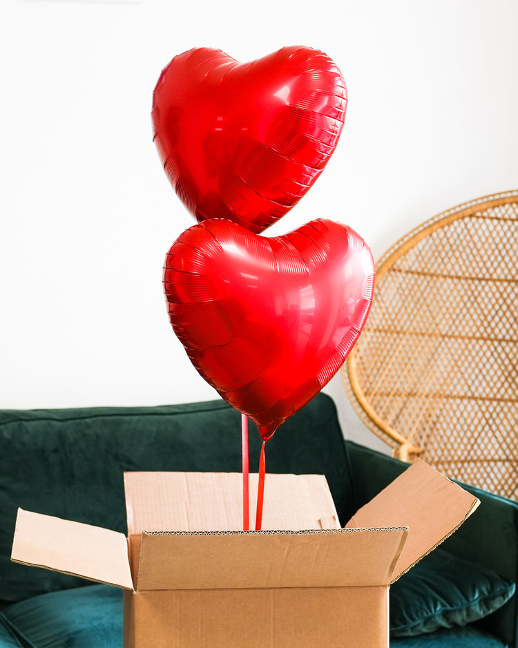 Box contenant deux ballons en forme de cœur rouge.