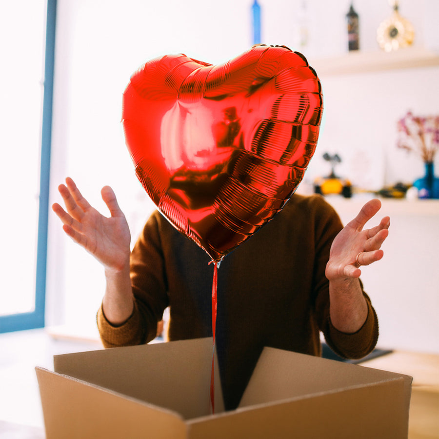 Ballon en forme de cœur rouge flottant avec une carte personnalisée.