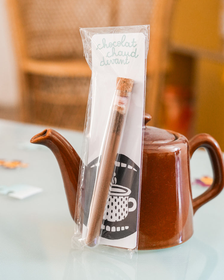 Tube à chocolat chaud avec étiquette colorée et bouchon doré.