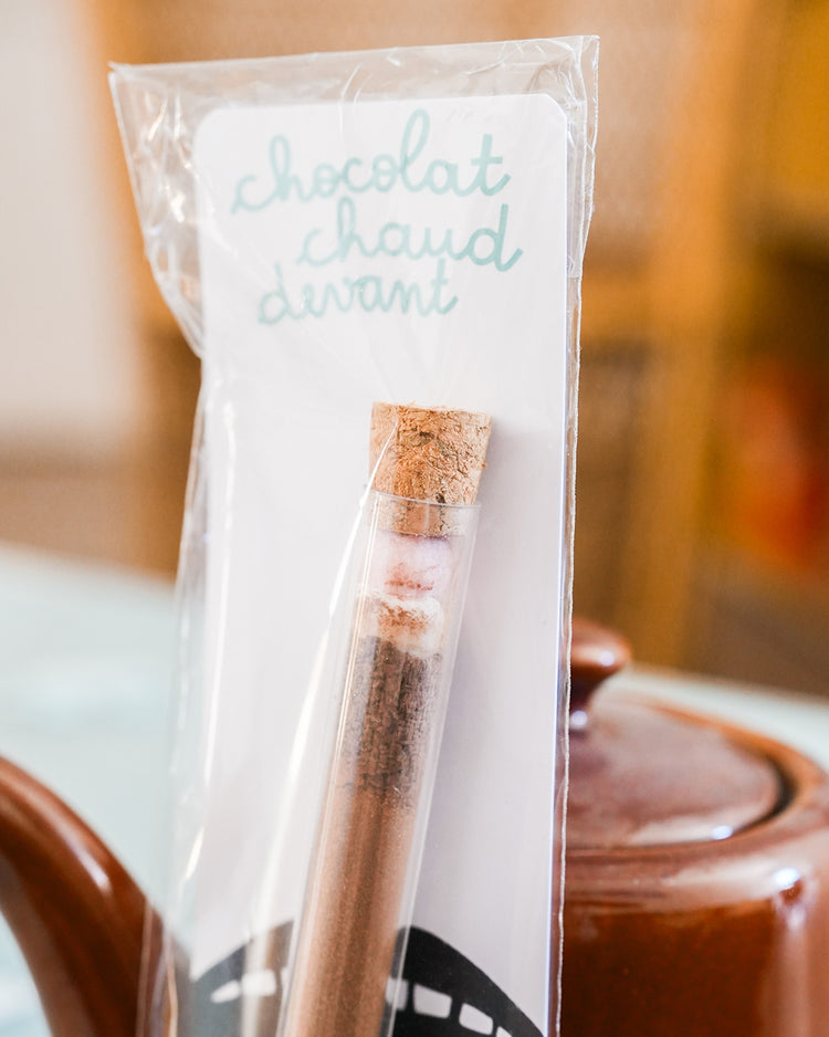 Tube à chocolat chaud avec étiquette colorée et bouchon doré.