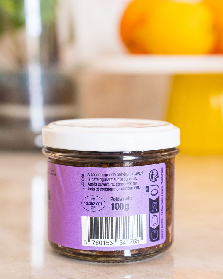 Pot de tapenade noire avec texture crémeuse et olives visibles.