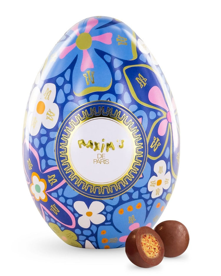 Oeuf Maxim's enrobé de chocolat au lait sur fond bleu