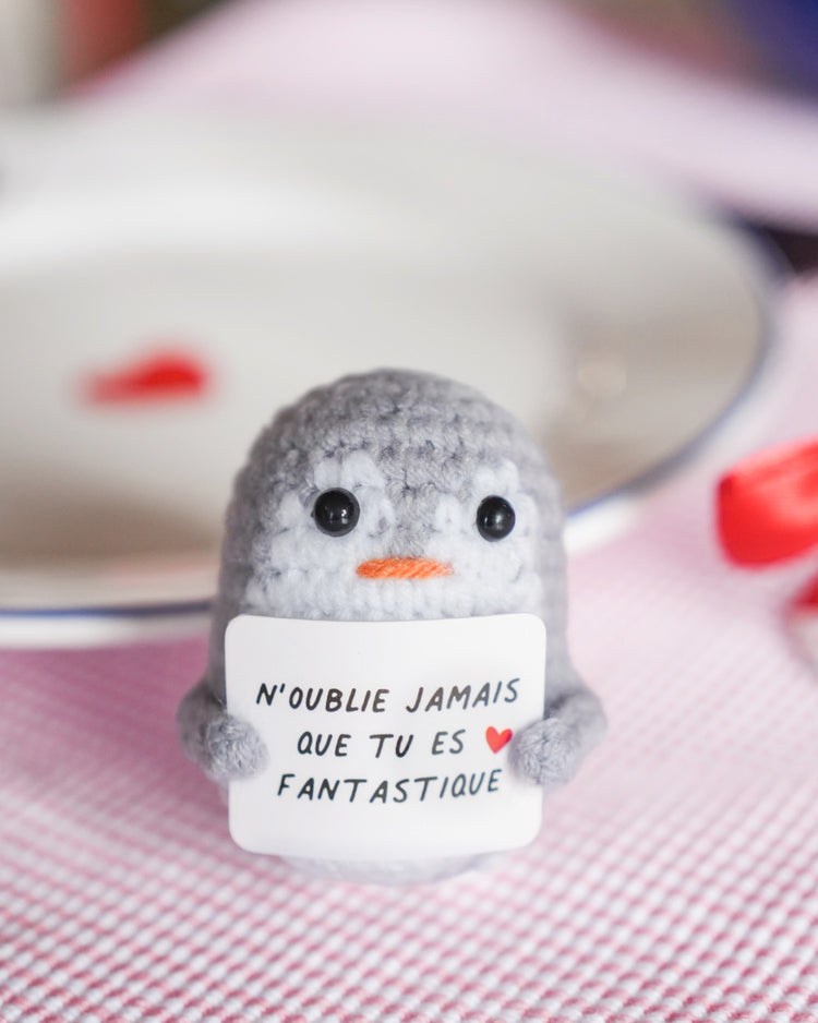 Peluche pingouin en crochet avec message inspirant sur son ventre.