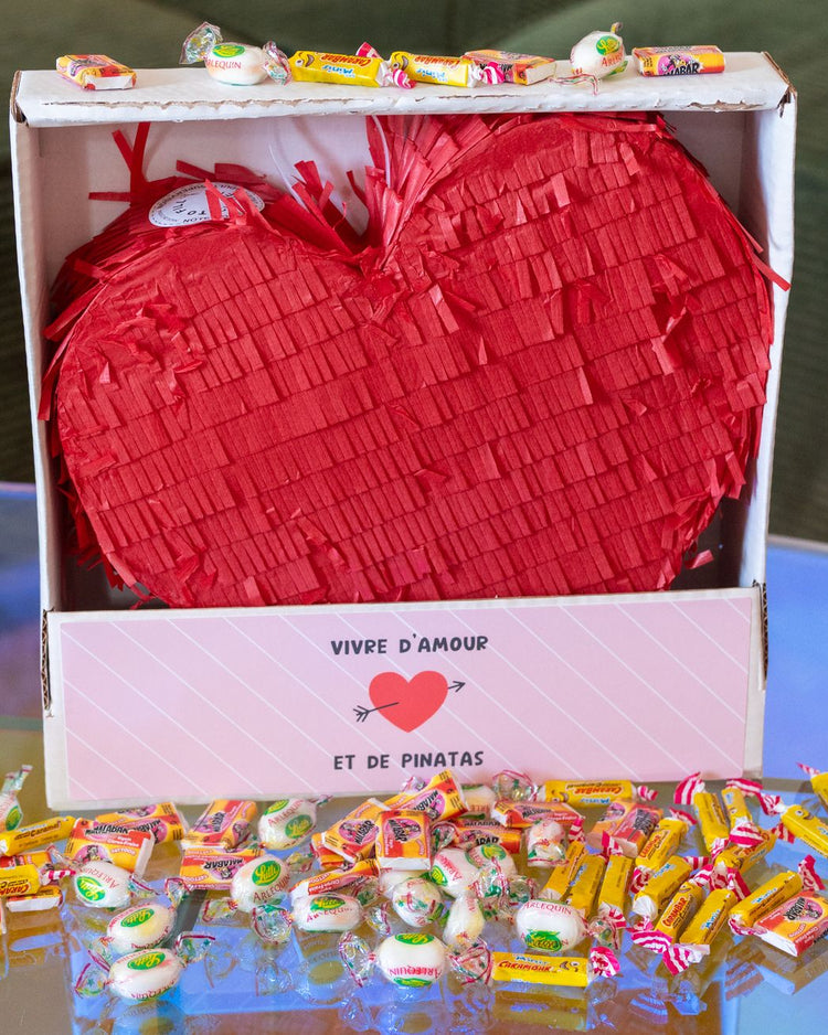 Piñata en forme de cœur avec bonbons colorés à l'intérieur.