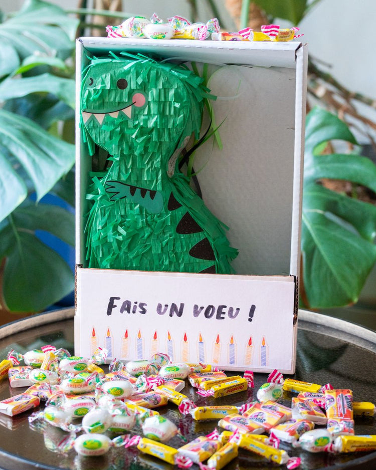 Piñata dinosaure colorée avec bonbons visibles à l'intérieur.