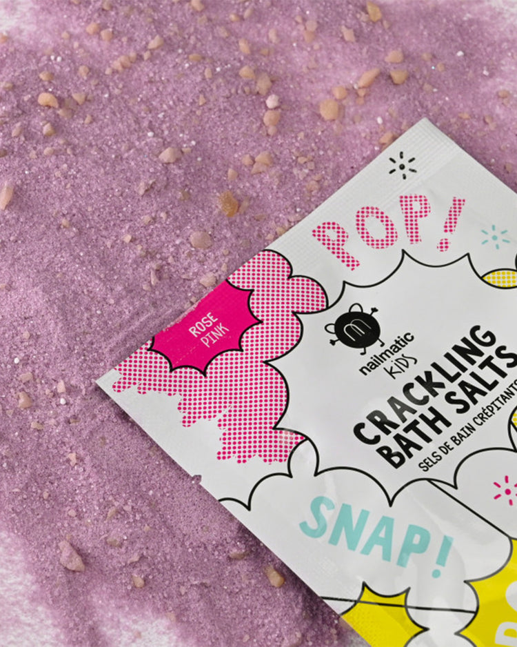 Sels de bain crépitants roses en gros plan sur une surface texturée.