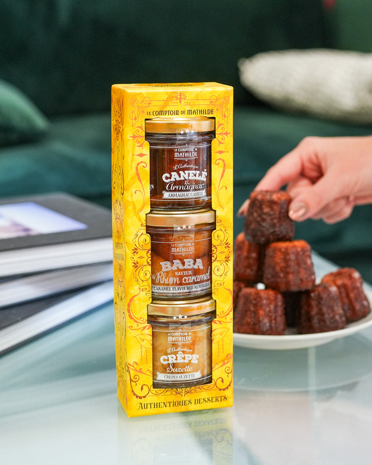 Coffret de desserts avec baba, canelé et crêpes en vue aérienne.
