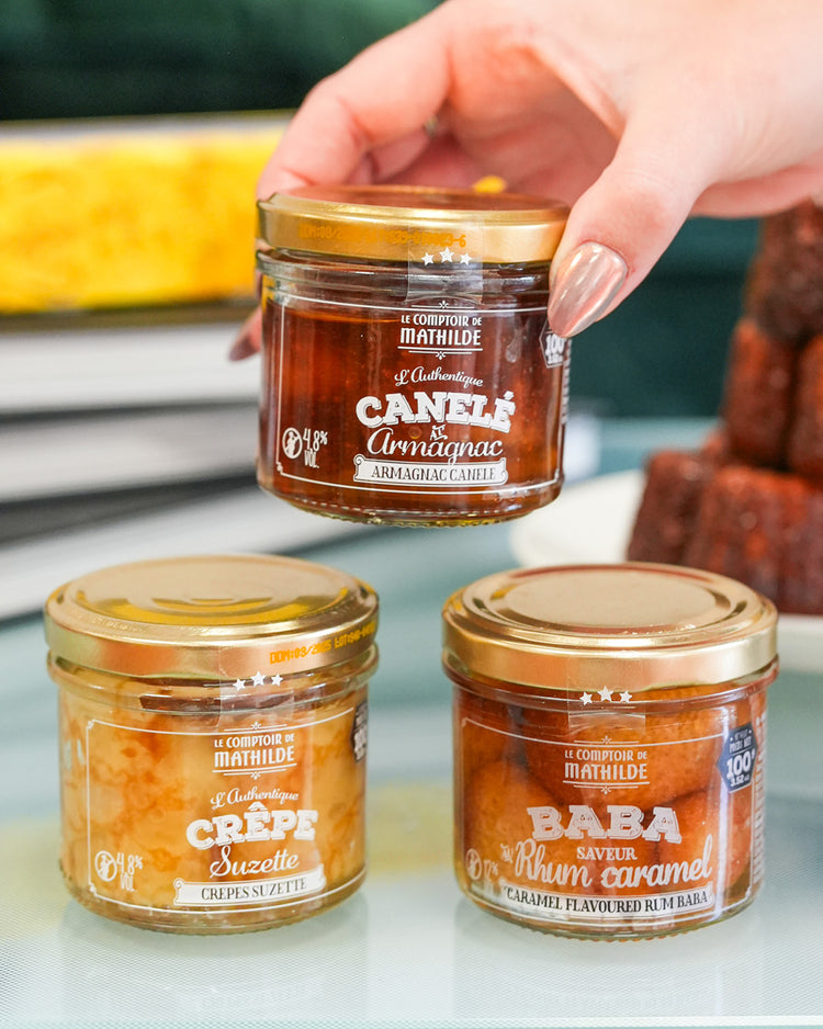 Coffret de desserts avec baba, canelé et crêpes en vue de dessus.