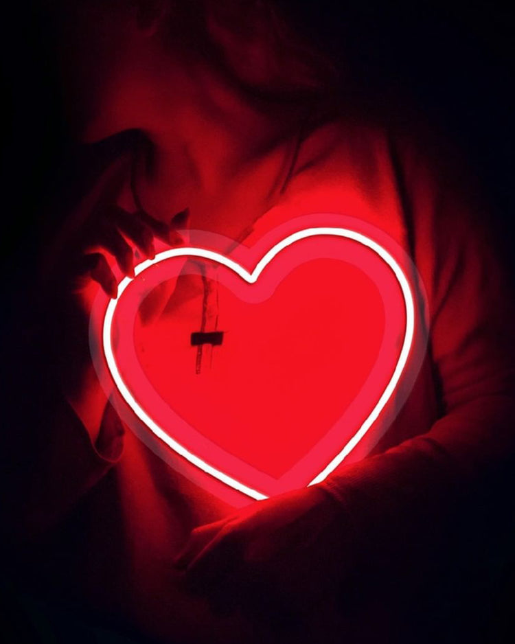 Néon en forme de cœur rouge éclatant sur fond neutre.