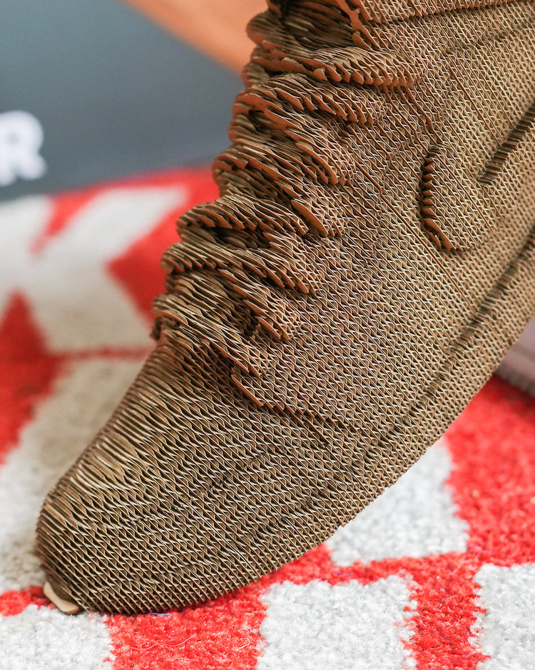 Sculpture en carton de sneakers vue de côté, détails précis.