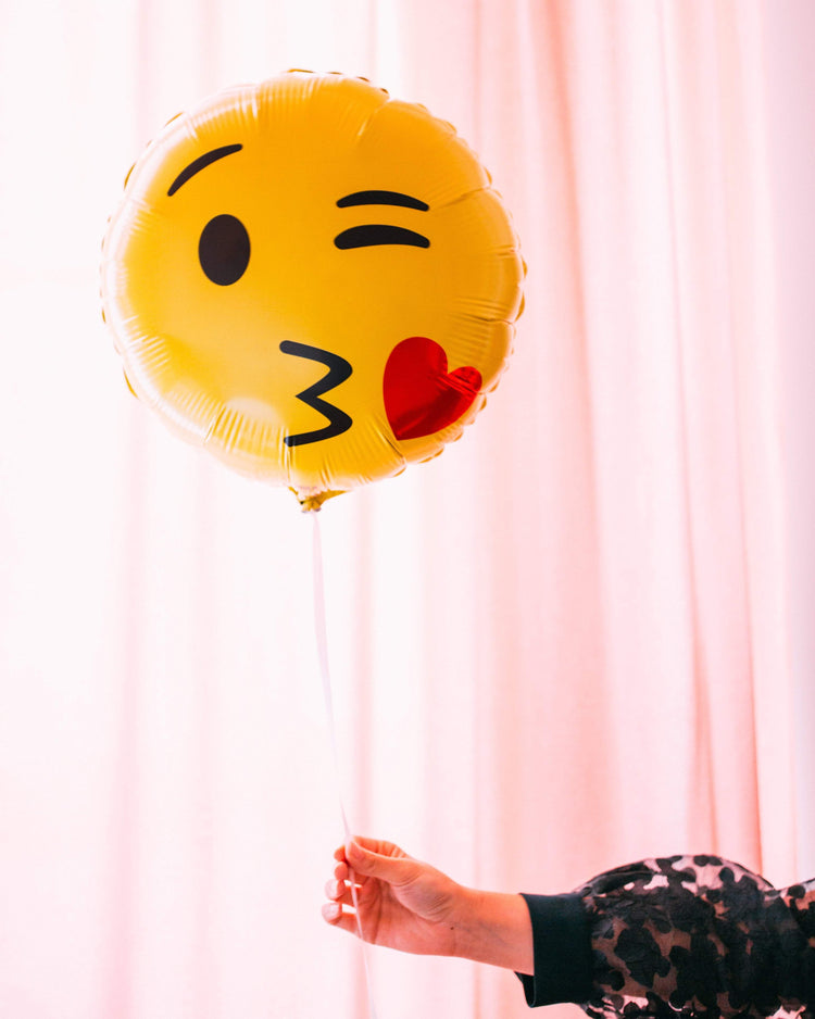 Ballon Emoji Bisous en forme de coeur rouge avec visage souriant, idéal pour exprimer l'amour et l'affection.