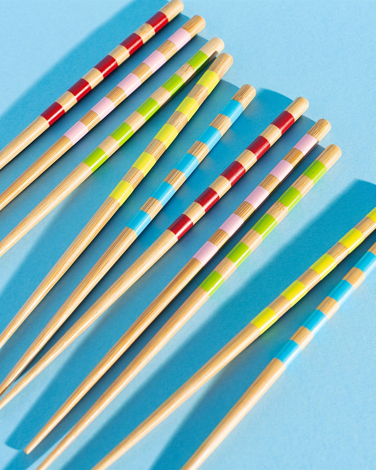Cinq baguettes en bambou avec motifs rayés colorés.