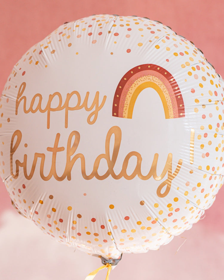 Ballon arc-en-ciel 'Happy Birthday' avec confettis colorés.