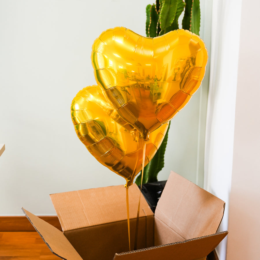 Box contenant deux ballons en forme de cœur dorés.