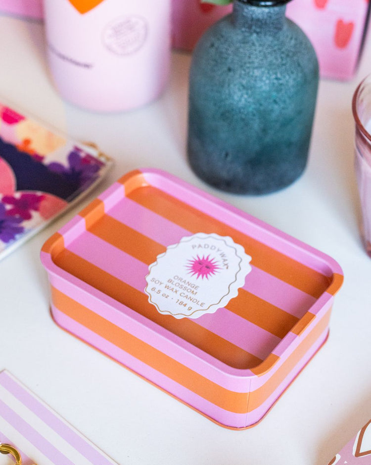 Bougie à 2 mèches avec rayures orange et rose, motif soleil.