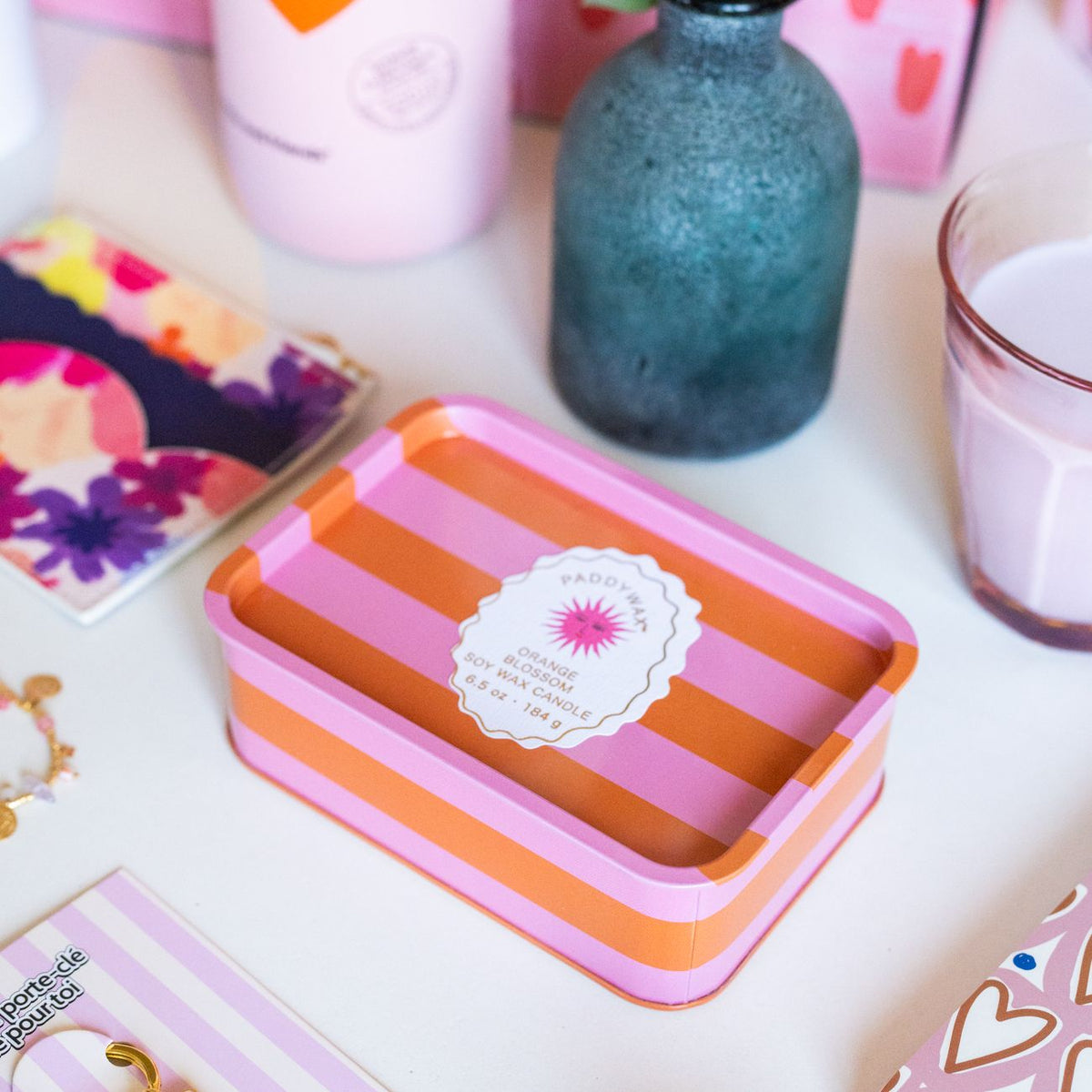 Bougie à 2 mèches avec rayures orange et rose, motif soleil.