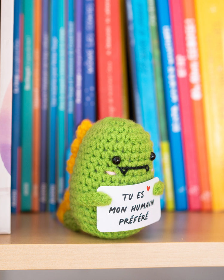 Dino en crochet tenant une pancarte avec un message affectueux.
