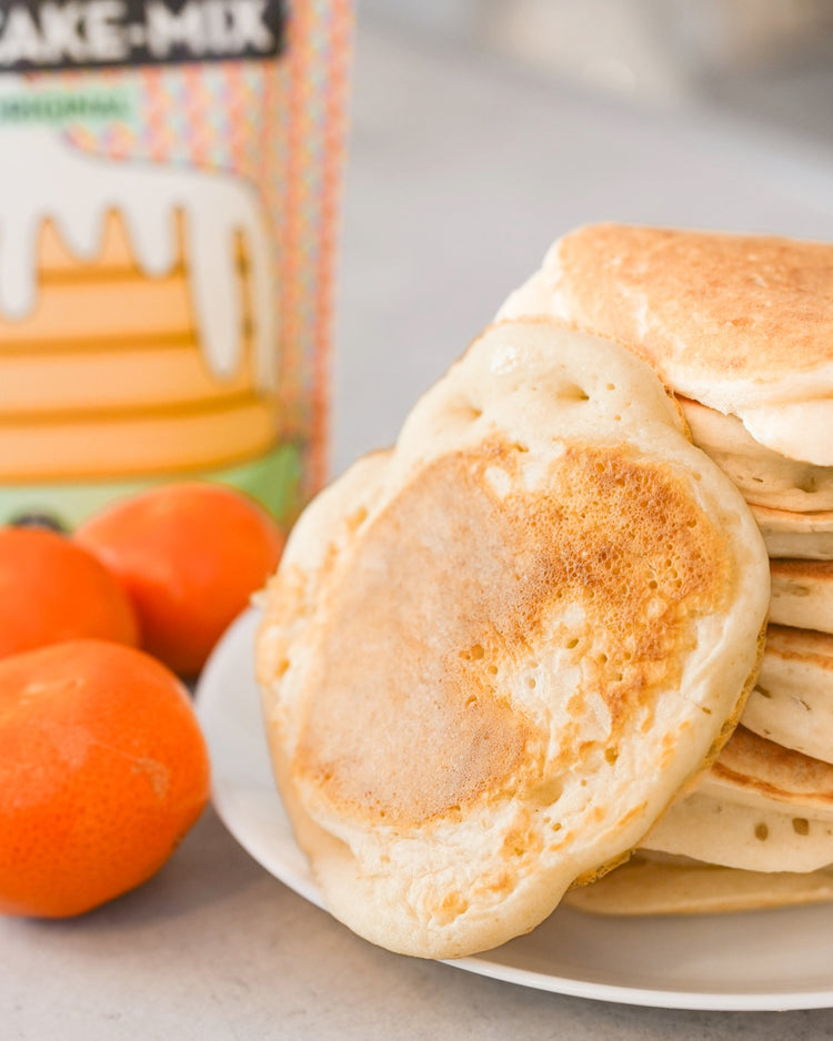 Kit DIY pancakes avec ustensiles et mélange en vue aérienne.