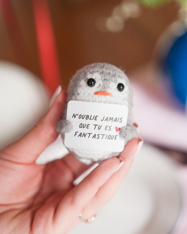 Peluche pingouin en crochet avec message inspirant sur le ventre.