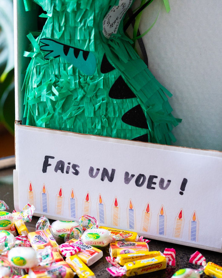 Piñata dinosaure colorée avec bonbons visibles à l'intérieur.