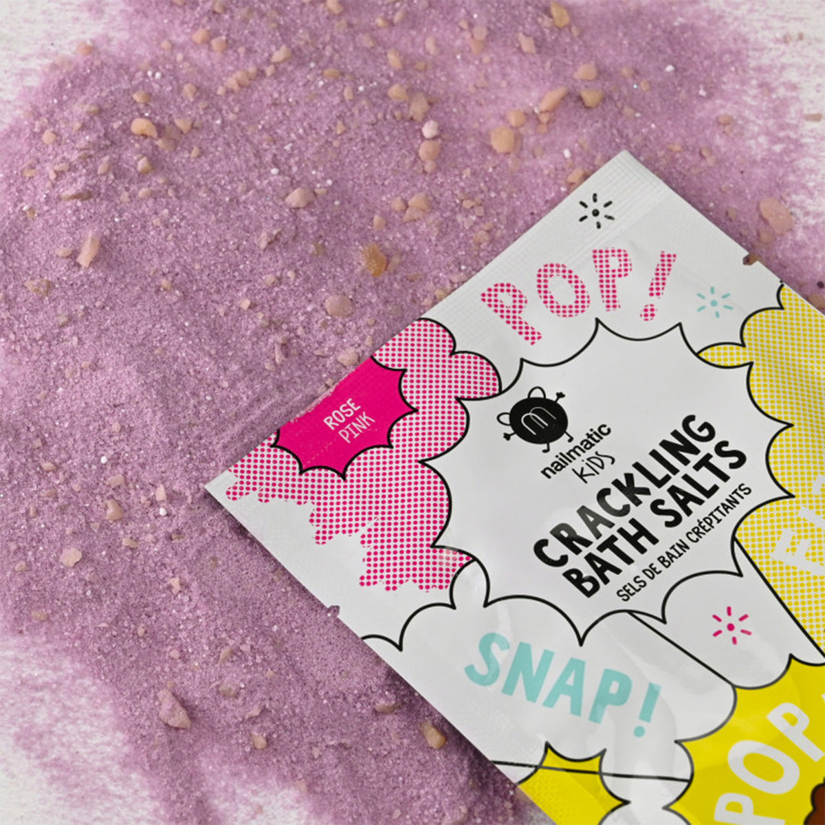 Sels de bain crépitants roses en gros plan sur une surface texturée.