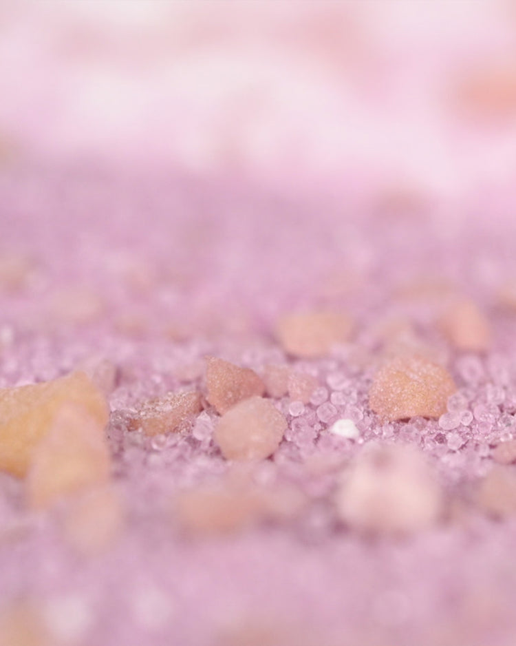 Sels de bain crépitants roses en gros plan sur fond clair.