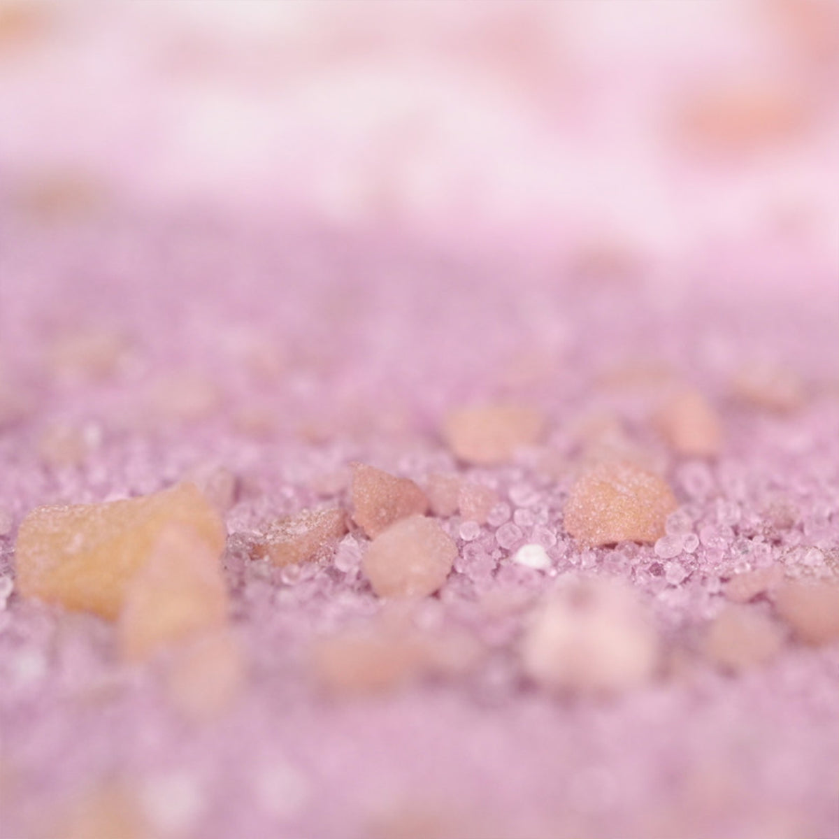 Sels de bain crépitants roses en gros plan sur fond clair.