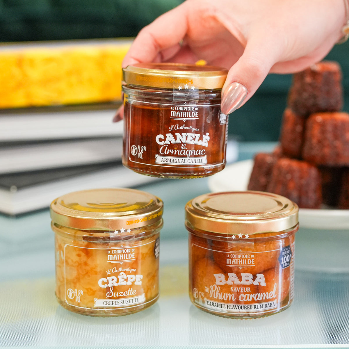 Coffret de desserts avec baba, canelé et crêpes en vue de dessus.