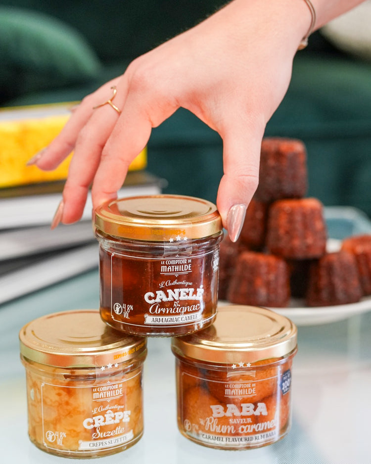 Coffret de desserts avec baba, canelé et crêpes en vue de dessus.