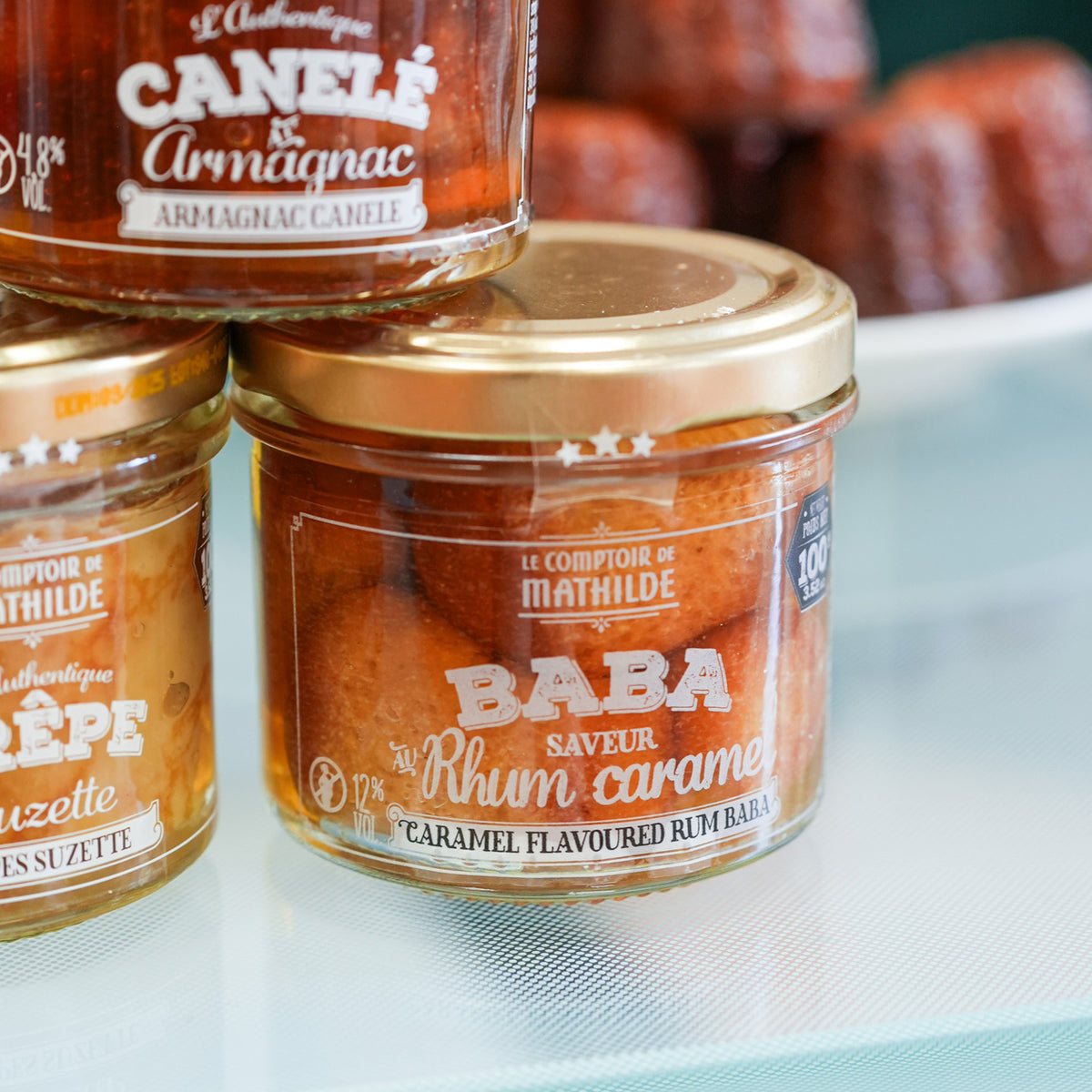 Coffret de desserts avec baba, canelé et crêpes sur fond clair.