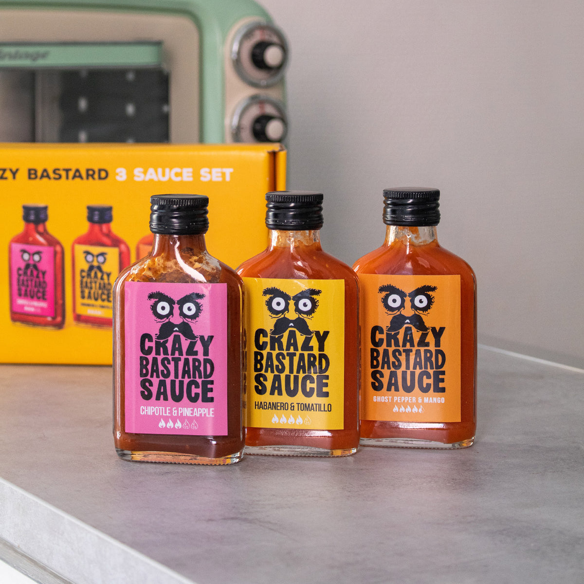 Trois flacons de sauces épicées sur fond blanc.