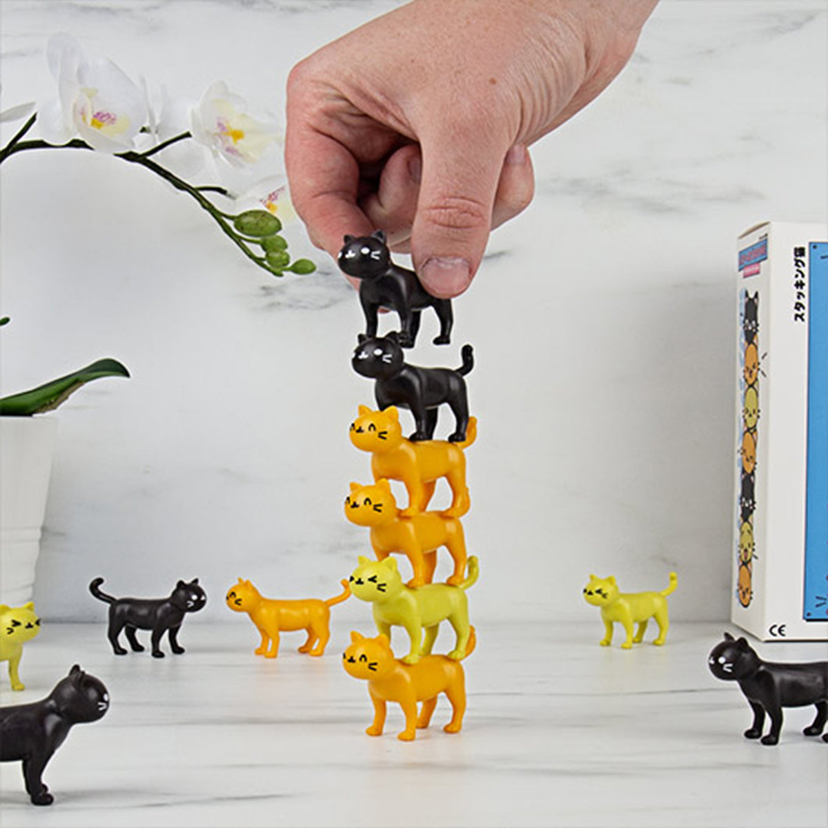 Jeu d'équilibre avec des chats colorés empilés en désordre.