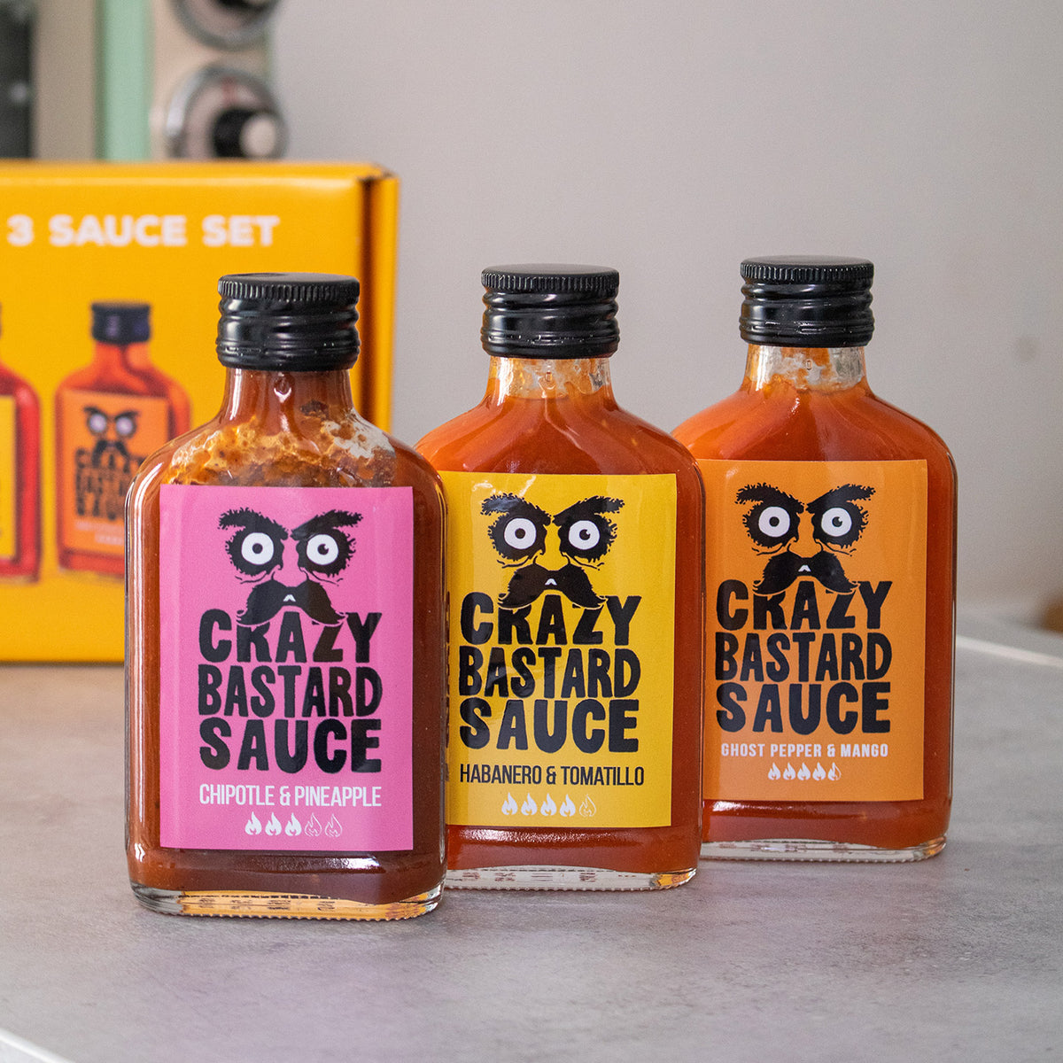 Trois flacons de sauces épicées sur fond blanc.