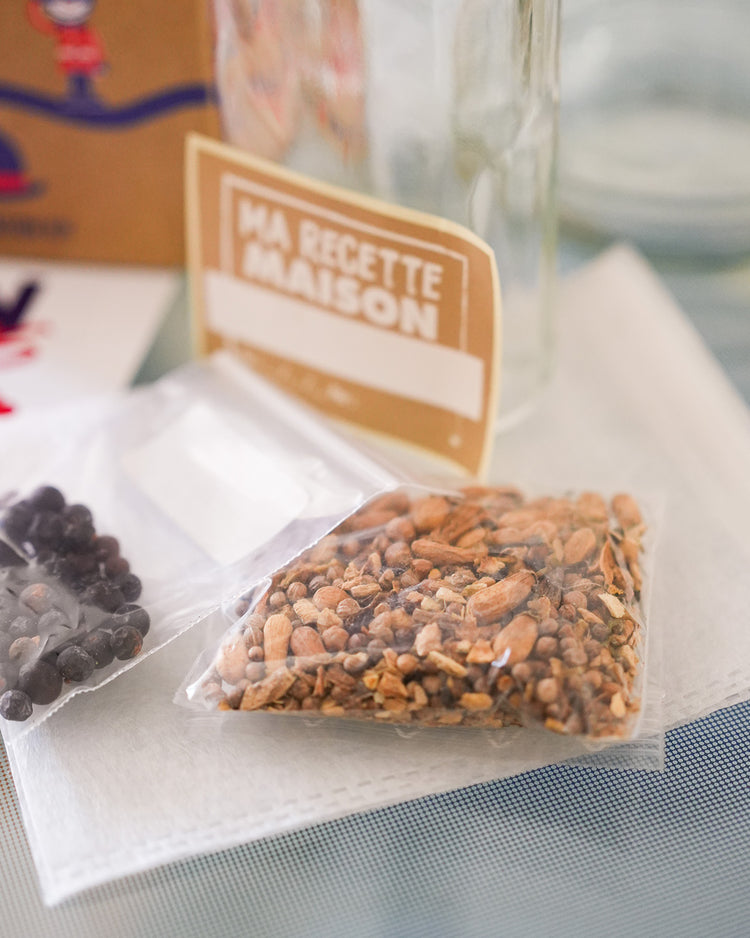 Kit DIY pour gin avec ingrédients et accessoires sur fond clair.