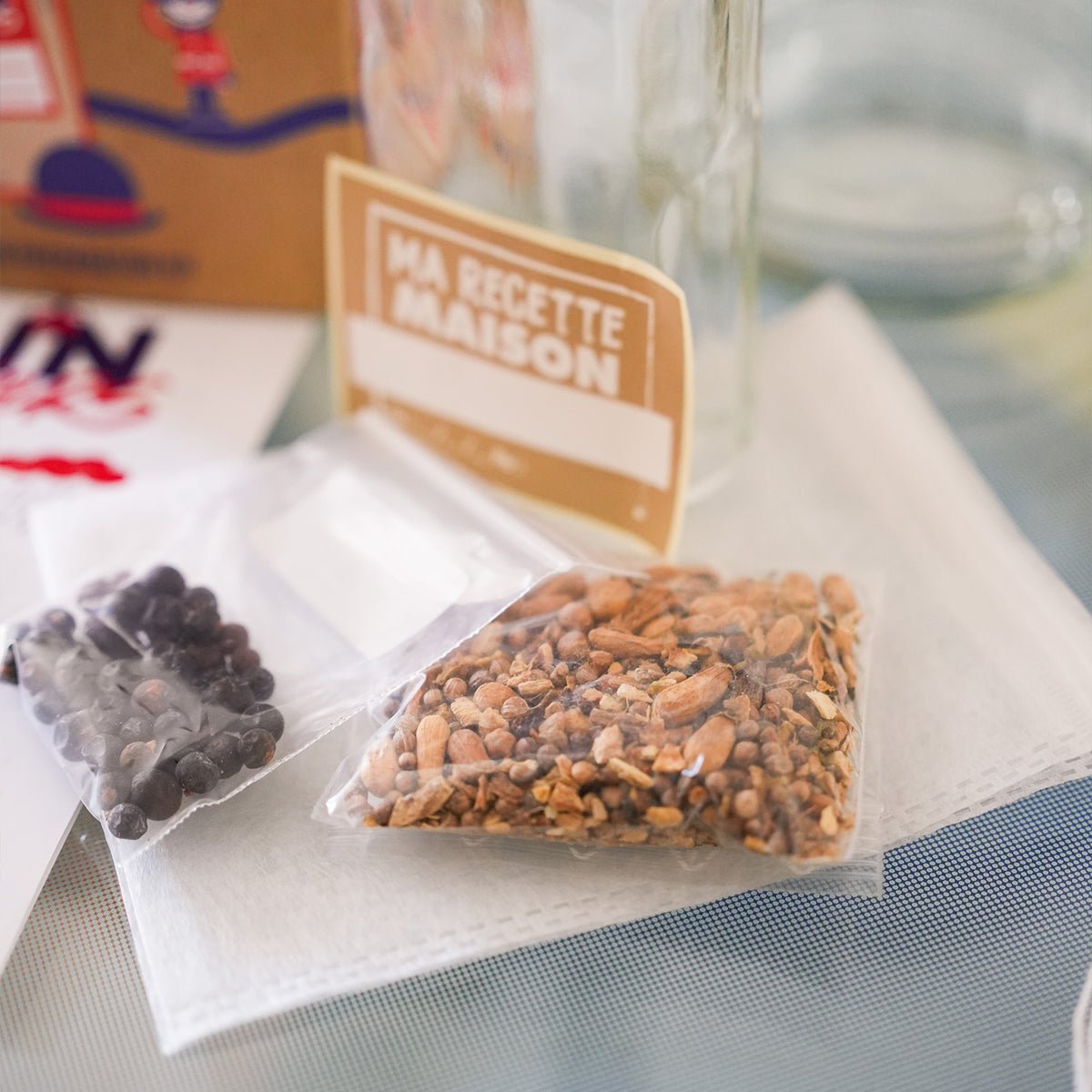 Kit DIY pour gin avec ingrédients et accessoires sur fond clair.