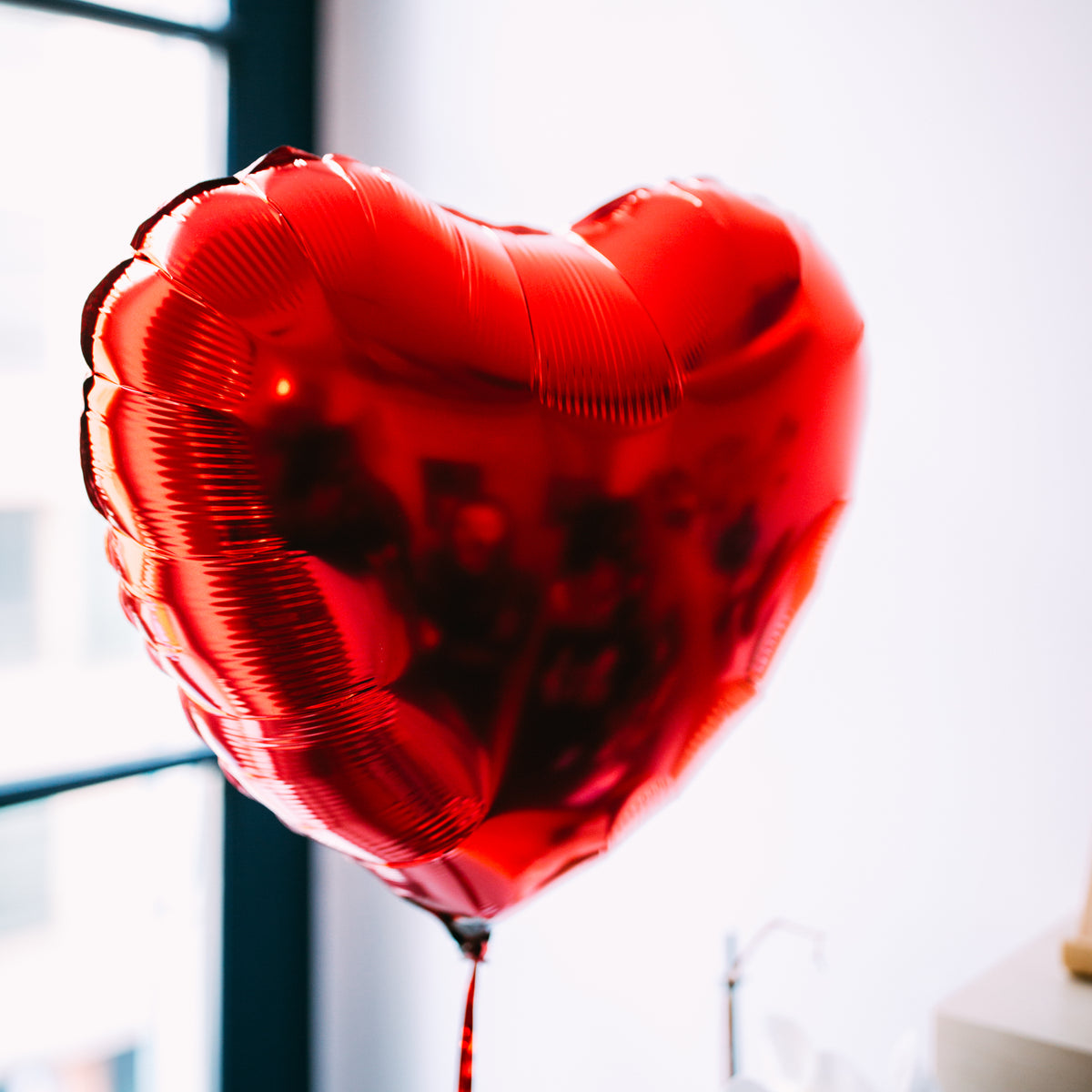 Ballon en forme de cœur rouge, texture lisse et brillante.